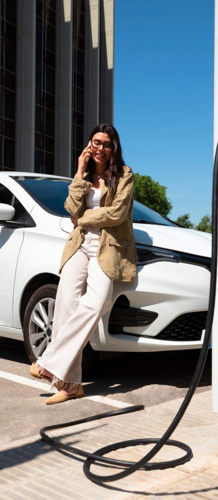 Cliente ao telefone junto a um carro elétrico a carregar